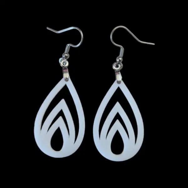 White teardrop-shaped earrings with flame-like cutouts, featuring three nested flame shapes inside a teardrop silhouette, hanging from silver hooks against a black background.