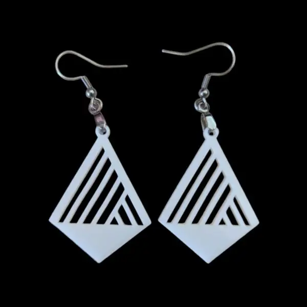 White diamond-shaped earrings with asymmetrical linear cutouts, featuring a bold geometric design, hanging from silver hooks against a black background.