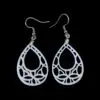 White geometric teardrop-shaped earrings with intricate cut-out design, featuring a web-like pattern inside a teardrop silhouette, hanging from silver hooks against a black background.