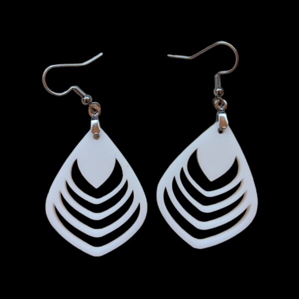 White teardrop-shaped earrings with a series of nested petal-like cutouts, creating a geometric floral effect, hanging from silver hooks against a black background.