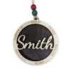 Circular wooden ornament with "Smith" laser-engraved in the center, surrounded by individual names. Hanging from twine with red and green beads.