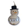 Wooden snowman-shaped ornament with a black top hat, orange carrot nose, and smiling face. The name "Jonah" is engraved across the body in white text, with "2024" at the bottom.