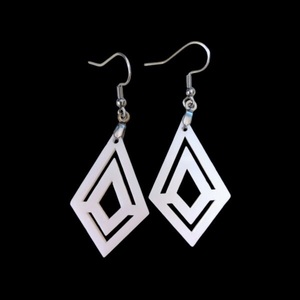 White geometric dangle earrings with diamond shape and angular cutouts, hanging from silver-tone hooks.