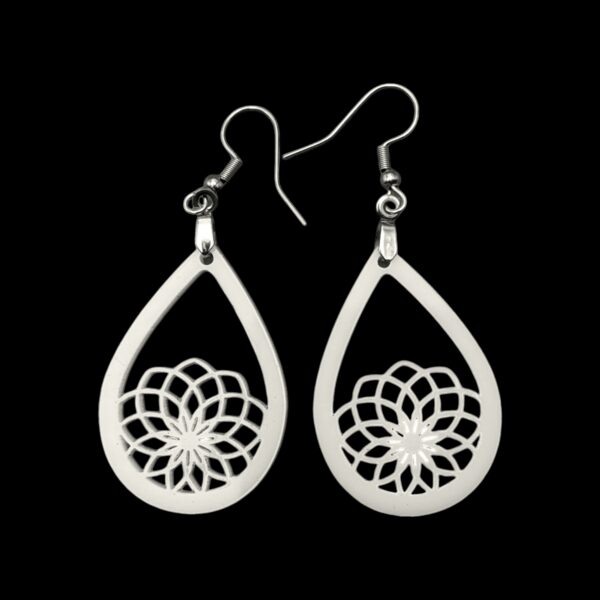 Close-up of white mandala earrings with intricate geometric design.