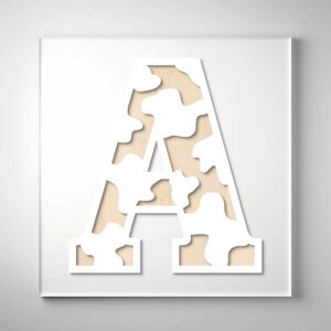 A cow print wooden letter "A" with a modern cutout design, layered over a light wood background.