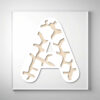 Laser-cut giraffe print wooden letter "A" with intricate cutout patterns over a light wood grain background.