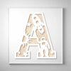 Laser-cut wooden letter "A" featuring an astronaut, rocket, sun, and stars over a natural wood grain background.