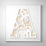 Laser-cut wooden letter "A" featuring an astronaut, rocket, sun, and stars over a natural wood grain background.